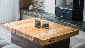 Une table basse en bois, sur laquelle reposent deux bocaux en verre, est posée sur un sol carrelé.