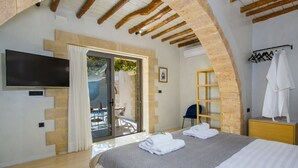 A bedroom with a bed, a TV, a wardrobe, and a bathroom visible through an archway. - Casa di Grimpili (Kolimvari)