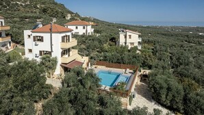 A residential area with multiple houses, a swimming pool, and a view of the sea. - Villa Hibiscus with private pool & bbq (Spilia)