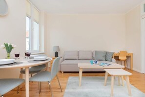 Un salon moderne comprenant un canapé, une table à manger avec des chaises, une petite table basse et une lampe.