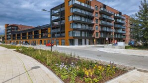 A multi-story apartment building with balconies, a parking area, and a landscaped garden. - Elegant Apartment | Balcony with View of the Motława River, Gymnasium (Gdansk)