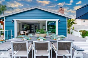 A dining area with a table set for four, white chairs, and a large bowl centerpiece. - Outdoor Haven with Spa, Sauna, Walk to LJ Shores (La Jolla)