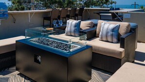 Ein Sitzbereich im Freien mit einem Glastisch, gepolsterten Sofas und einem integrierten Grill.