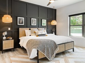 Un dormitorio moderno con cama, mesitas de noche y cuadros en la pared.