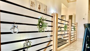 A hallway with wooden railings, framed botanical prints, and potted plants. - Luxury at Lake Taneycomo, Hot Tub, FirePit, Views! (Hollister)