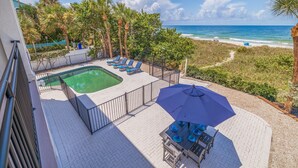 A rooftop pool area with a hot tub, lounge chairs, and a table with blue tableware.