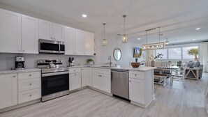 A modern kitchen with white cabinetry, stainless steel appliances, and a central island.