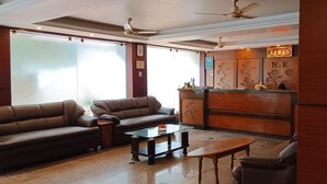 A modern living room with leather sofas, a glass coffee table, and a wooden reception desk.