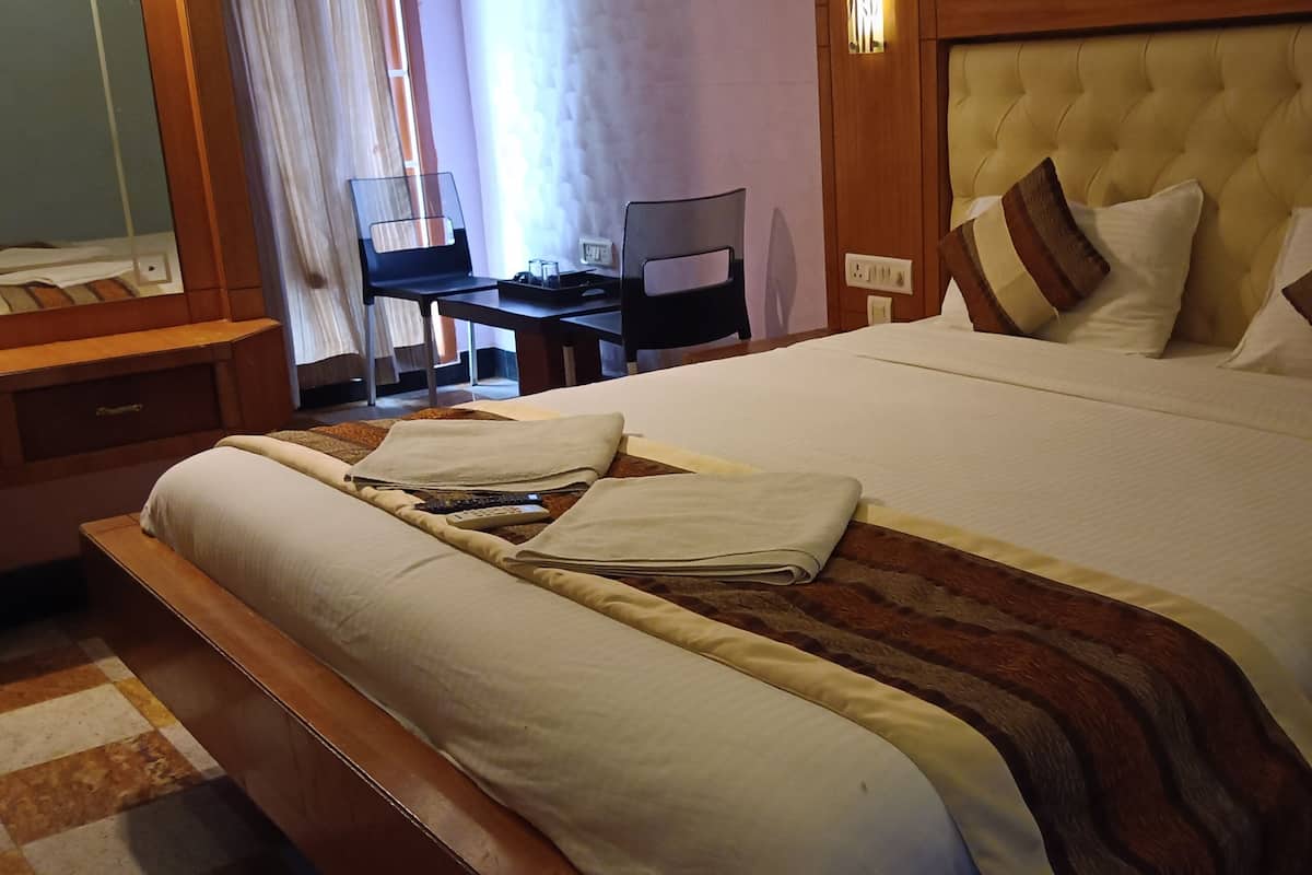 A hotel room with a large bed, a desk, and a chair.