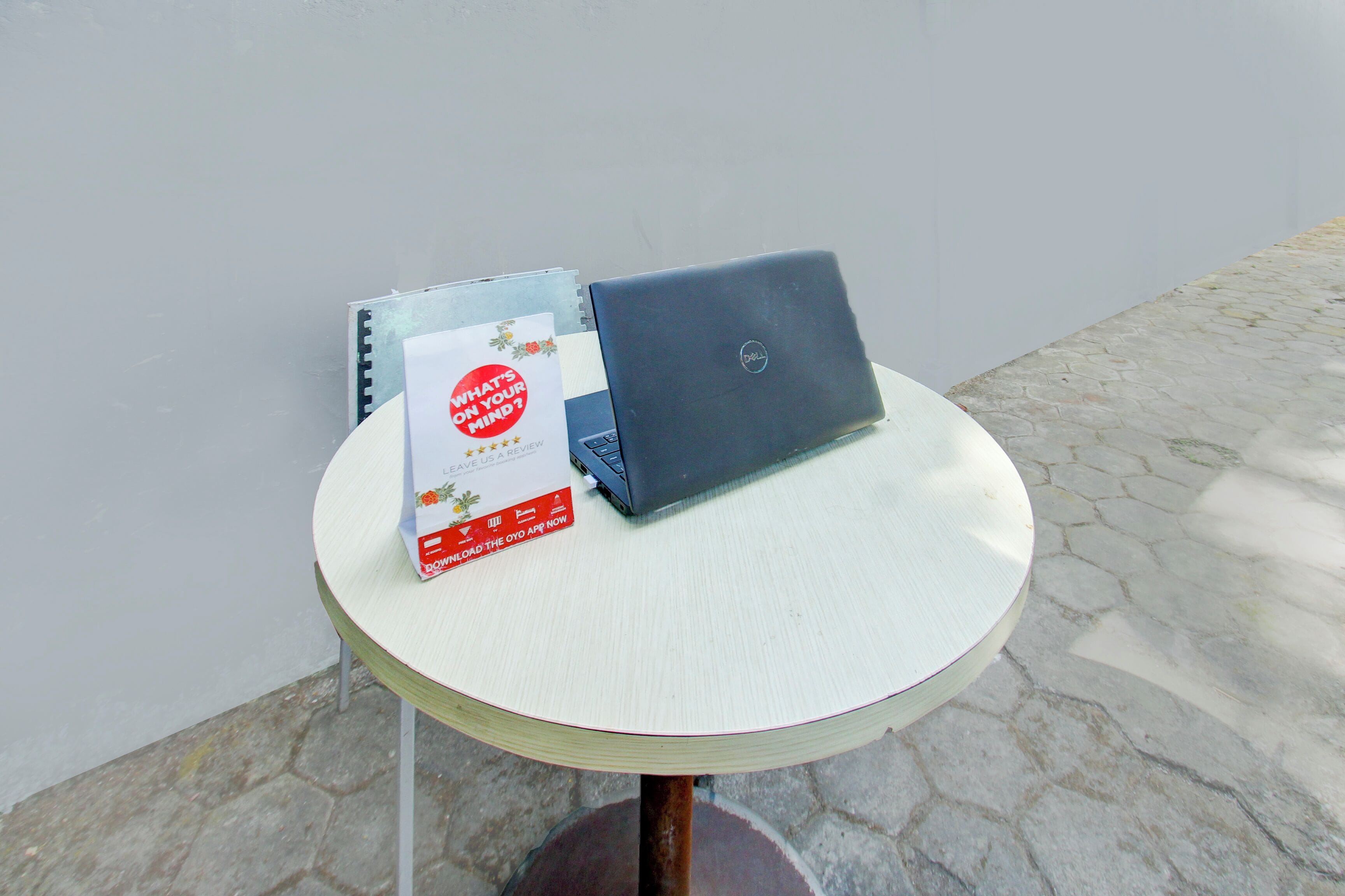 Una laptop sobre una pequeña mesa redonda con un folleto a un lado.