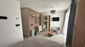 Ein modernes Schlafzimmer mit einem großen Bett, einem Schminktisch mit Spiegel, einem Kleiderschrank, einem runden Couchtisch und einem an der Wand befestigten Fernseher.