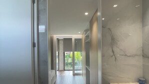 Une salle de bain moderne avec un plancher en bois, un meuble-lavabo en marbre et une vue sur la verdure.