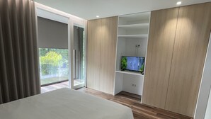 Une chambre moderne avec un grand lit, un plancher en bois, une télévision et une porte coulissante donnant sur un balcon.
