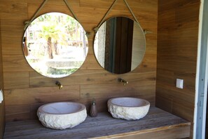 Ein rustikales Badezimmer mit zwei Steinsinkens, Holzwänden und zwei runden Spiegeln.