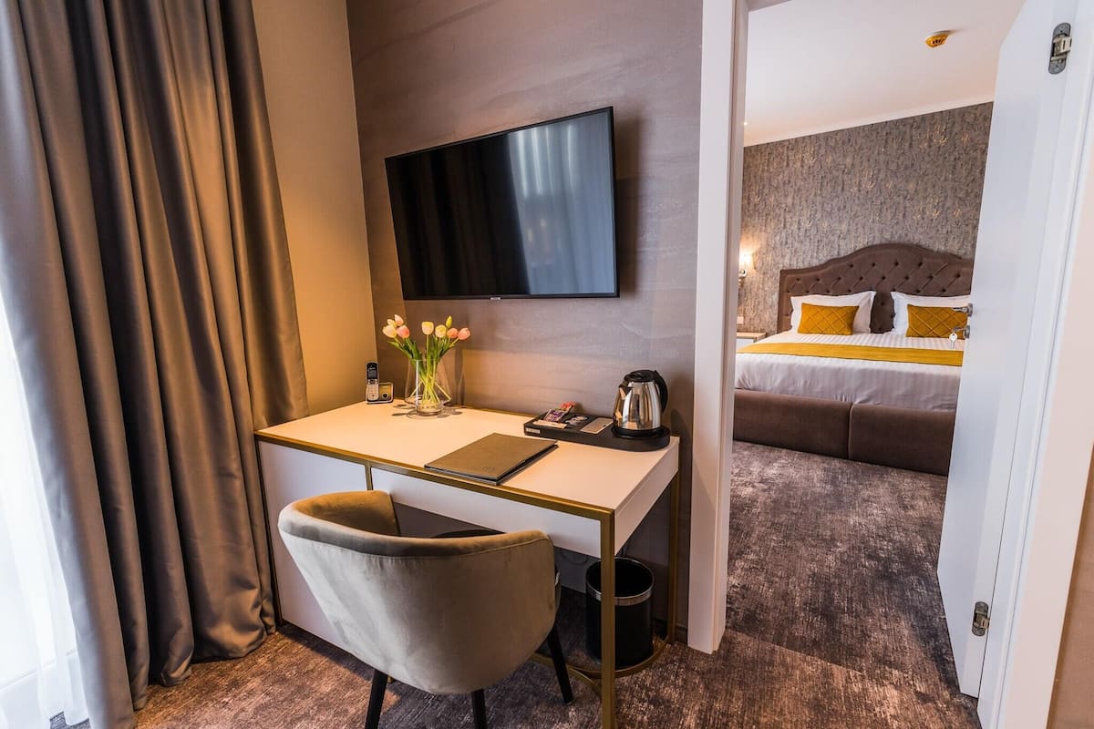 Une chambre d’hôtel équipée d’un bureau, d’une chaise, d’une télévision, d’un lit et d’une petite poubelle.
