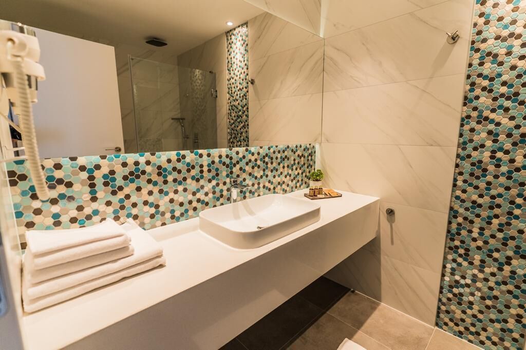 Une salle de bain moderne avec un lavabo blanc, un miroir et un espace douche.