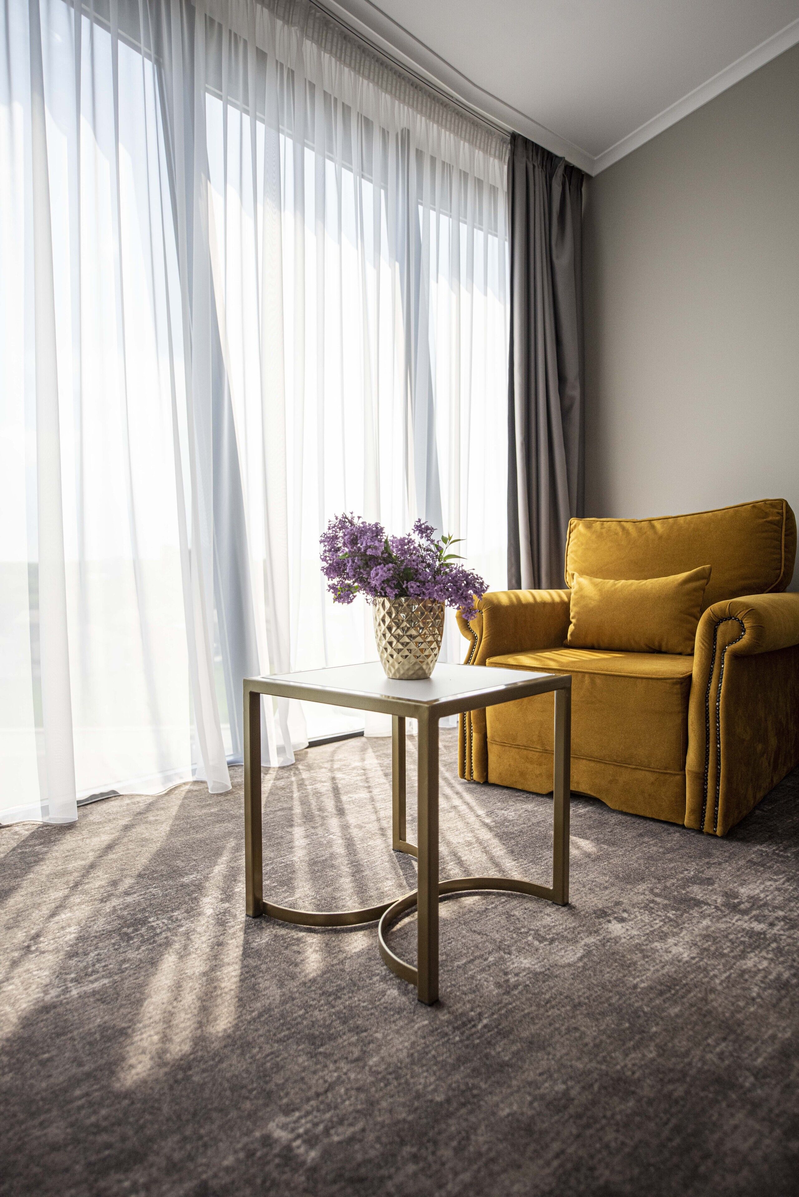 A room with a sofa, a small table, and a vase of flowers.