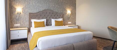 Una habitación de hotel moderna con una cama grande, dos mesitas de noche y una silla.
