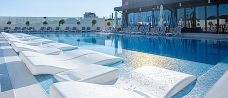 Una piscina techada, una piscina al aire libre de temporada, sombrillas