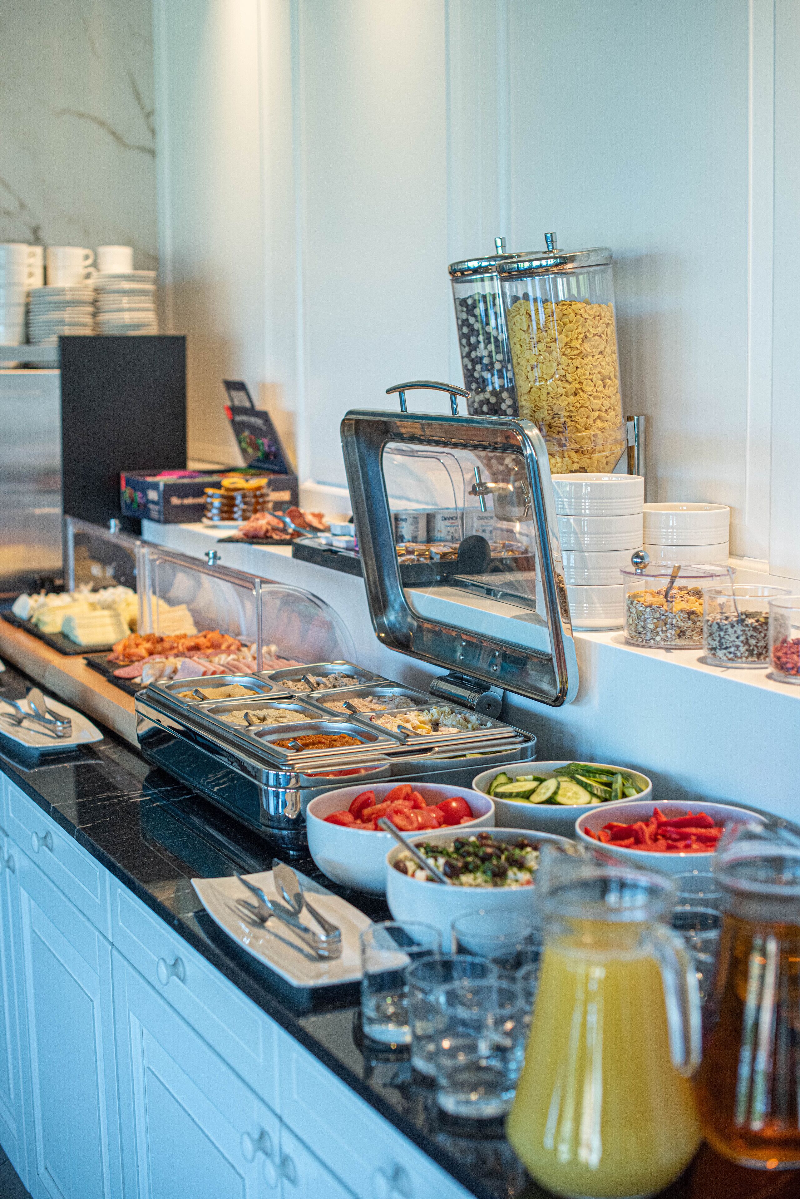 A buffet with various food items and a juice dispenser.