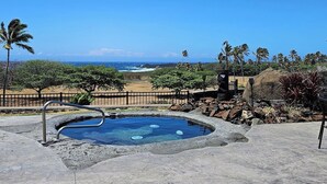 Un jacuzzi con vista despejada al océano y un paisaje rocoso con palmeras.