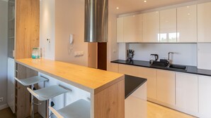 Une cuisine moderne dotée d’un plan de travail en bois, d’une hotte en acier inoxydable et de meubles blancs.