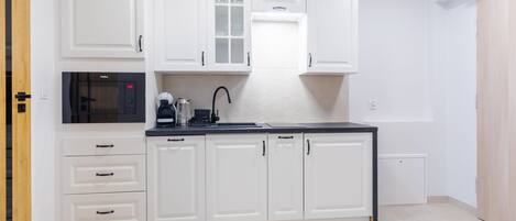 A modern kitchen with white cabinetry, a black countertop, and a built-in oven.