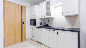 Una cocina moderna con armarios blancos, encimera negra y puerta de madera.