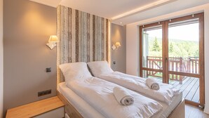 Un lit double avec du linge de lit blanc, une tête de lit en bois et deux lampes de chevet.