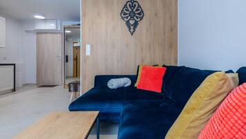 A modern living room with a dark blue sofa, a wooden accent wall, and a small wooden table.