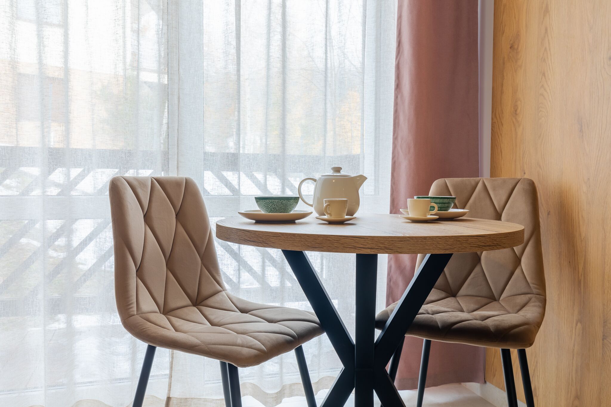 Una habitación con dos sillones mullidos y una mesa redonda con tetera y tazas.