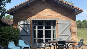 A rustic cabin with a wooden deck, a covered patio area, and a large sliding door. - Domaine Au Bon, La Sud - 5min D'hossegor (Angresse)