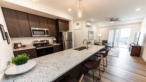 A modern kitchen with dark wood cabinets, stainless steel appliances, and a granite countertop.