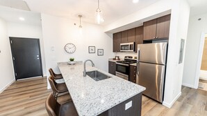 A modern kitchen with a granite countertop, stainless steel appliances, and a dark wood cabinet.