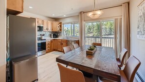 A modern kitchen with wooden cabinets, stainless steel appliances, and a large dining table with chairs. - 2 Bedroom Townhome with Private Garage!! (Frisco)