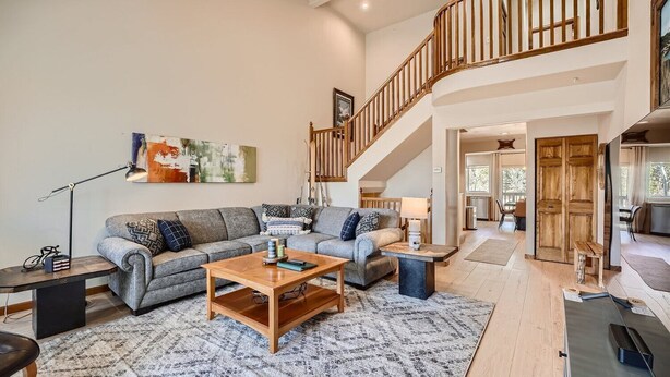 A spacious living room with a grey sofa, wooden coffee table, and a staircase leading to an upper level. - 2 Bedroom Townhome with Private Garage!! (Frisco)