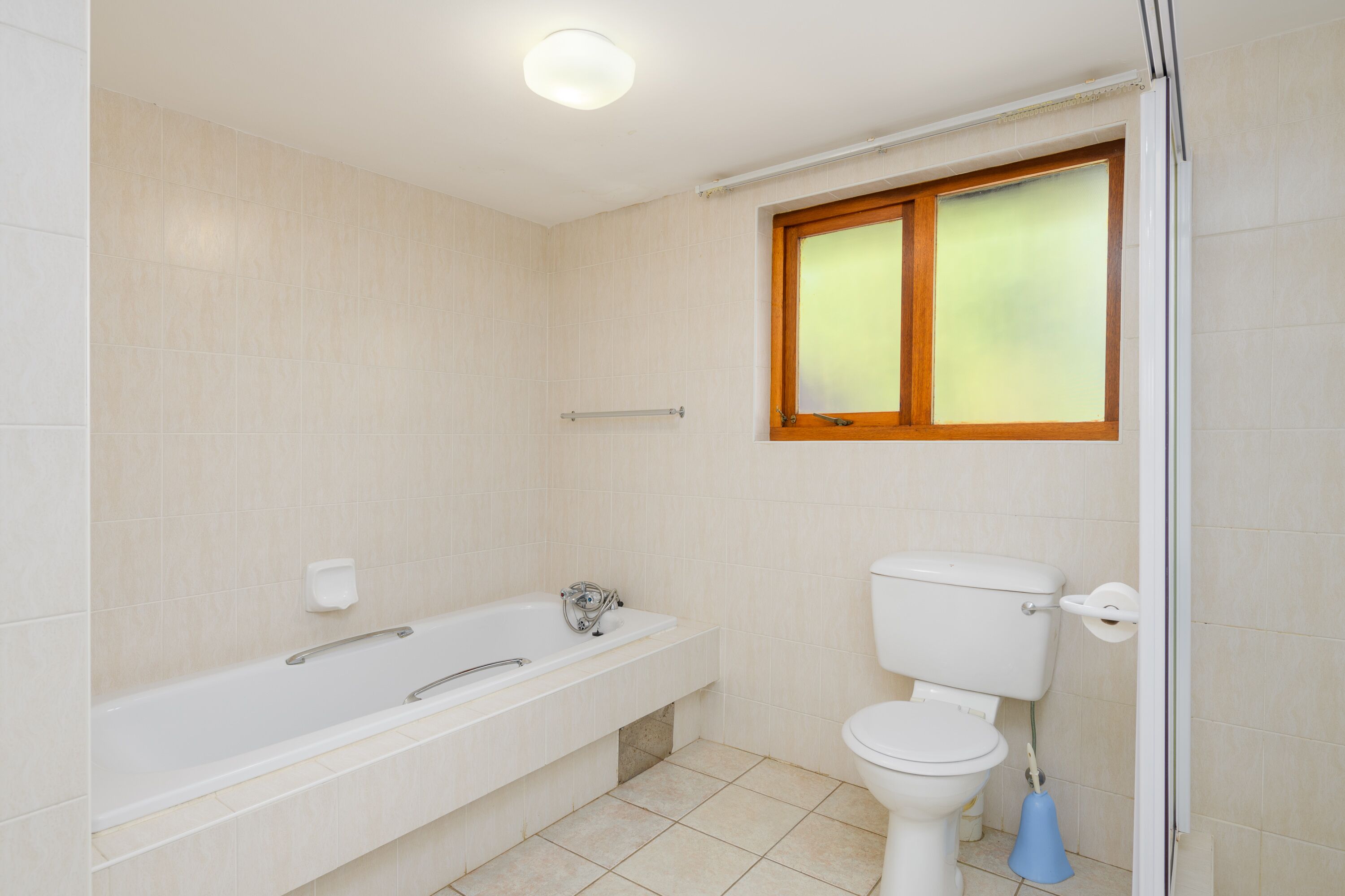 Een badkamer met een bad, toilet en een raam.