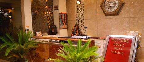 A reception desk with a sign reading "WELCOME HOTEL MOTI PALACE".