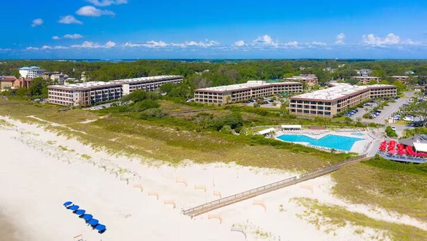 Un complexe hôtelier comprenant plusieurs bâtiments, une plage et une piscine.