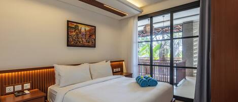 A hotel room with a large bed, a nightstand, a painting on the wall, and a window with a view of the outdoors.