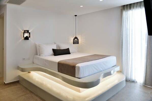 Un dormitorio moderno con una cama, dos luces fijadas a la pared y un ventanal con cortinas.
