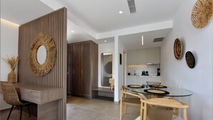 Une cuisine moderne dotée d’un îlot central, d’un coin repas avec une table en verre et d’un espace détente avec un canapé.