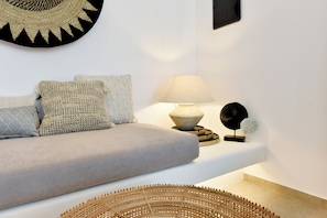 Una sala de estar moderna con un sofá, cojines, una lámpara y objetos decorativos sobre una consola blanca.