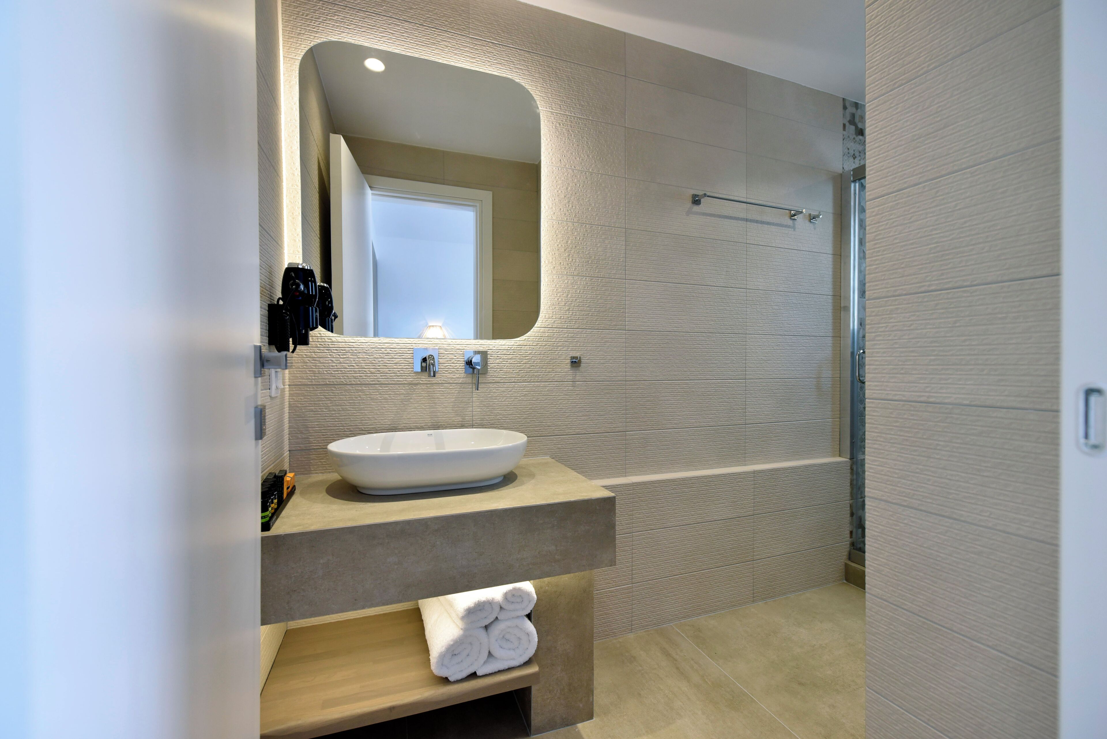 Une salle de bain moderne avec un grand lavabo, un miroir et un espace douche.