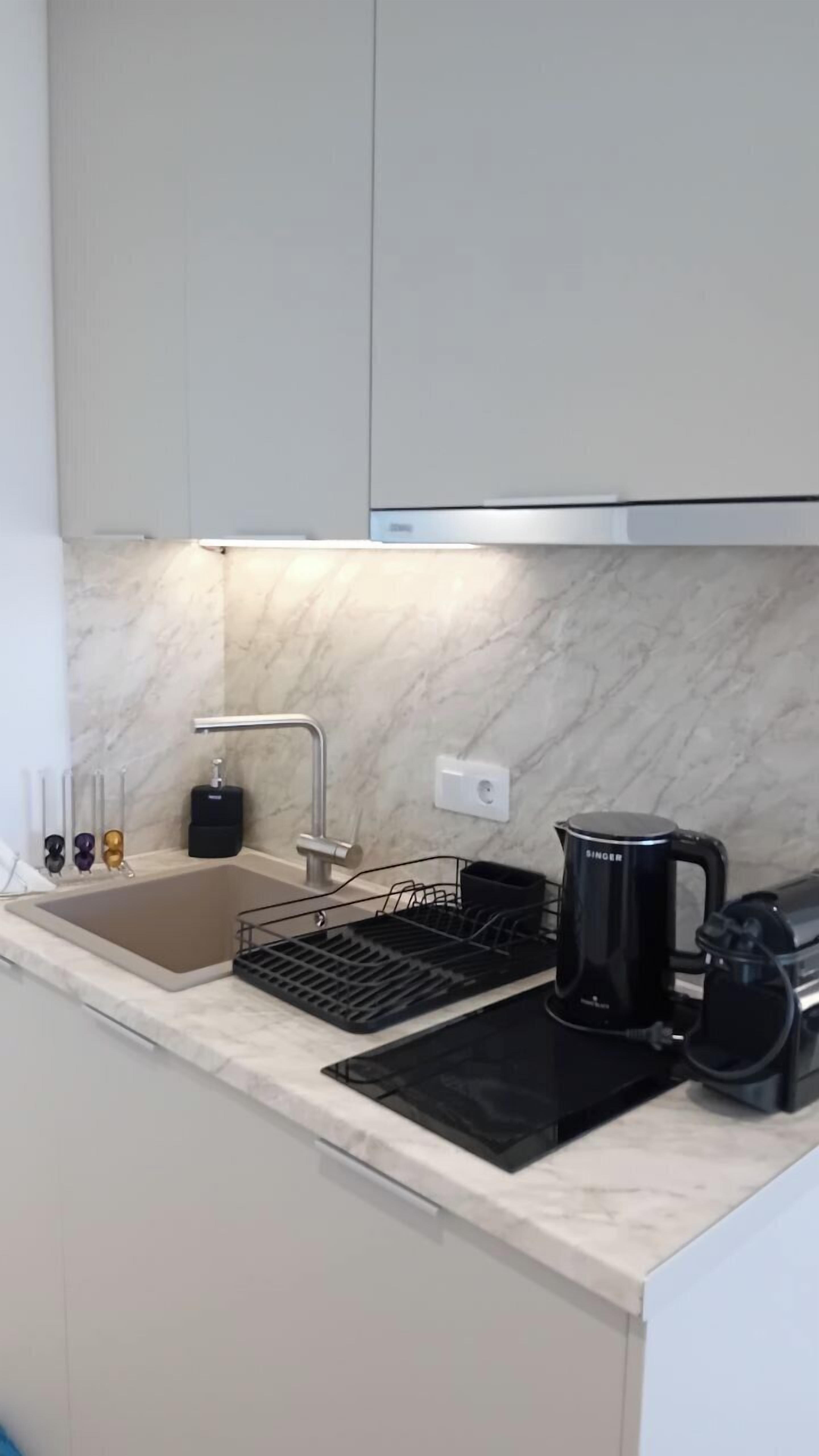 A kitchen with a sink, a coffee maker, and a kettle.