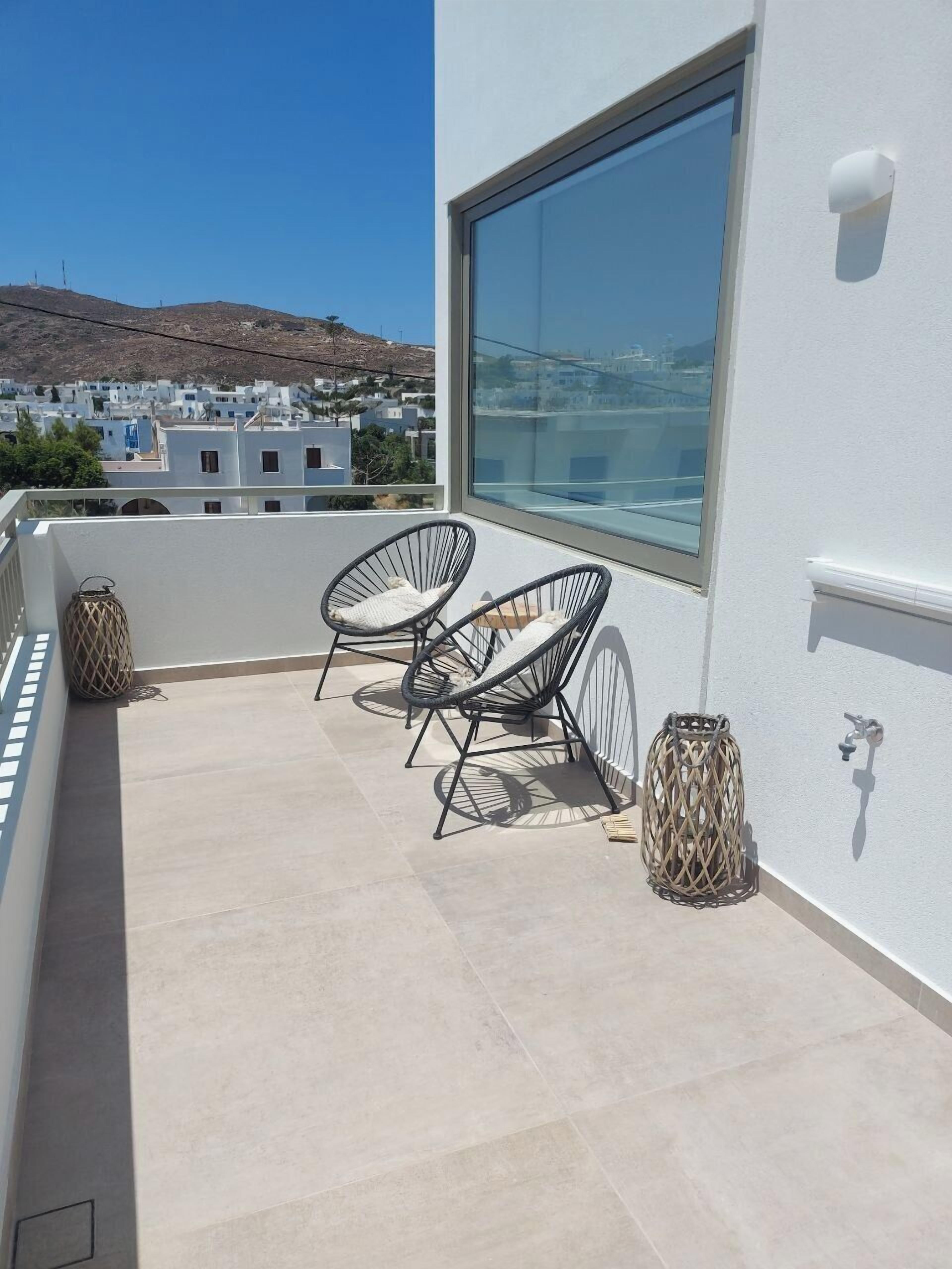 A balcony with two wicker chairs, a small table, and a lantern.