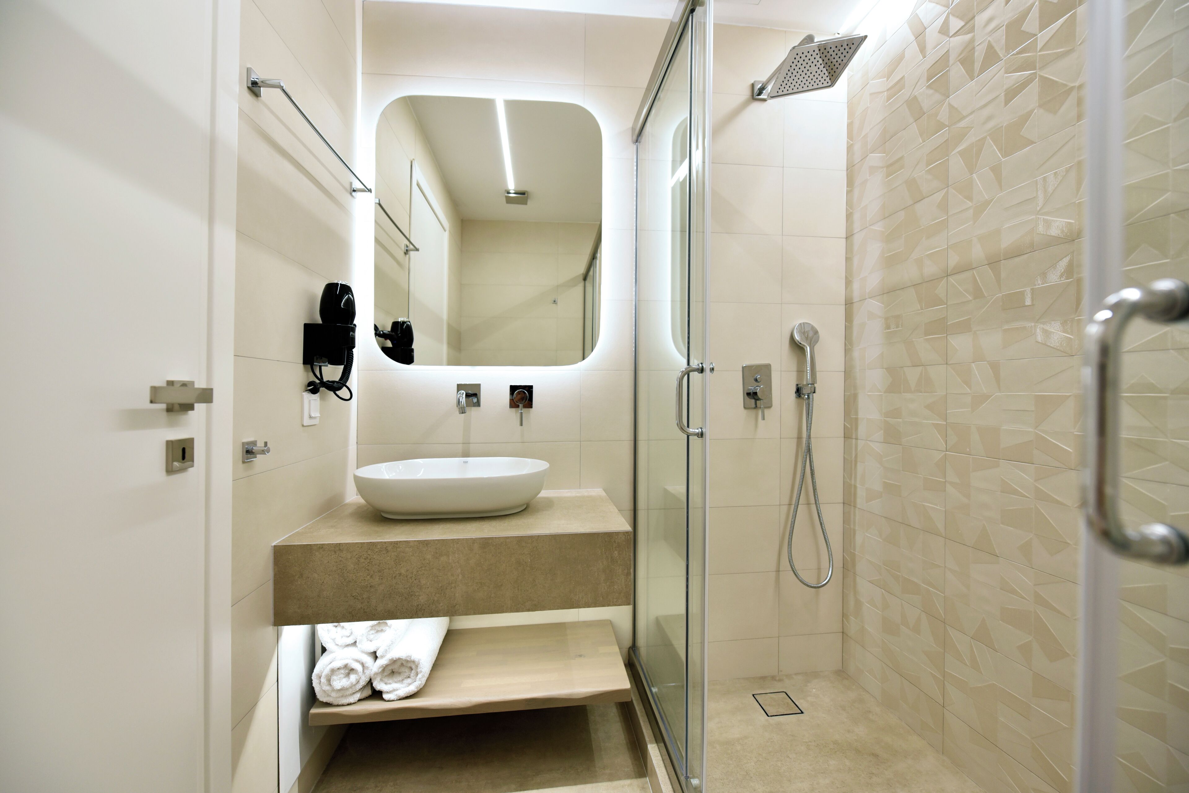A modern bathroom with a glass-enclosed shower, a large mirror, and a built-in sink.