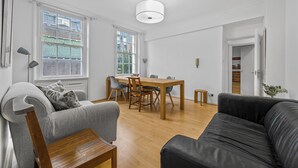 Un salon moderne avec un canapé gris, un canapé en cuir noir, une table basse en bois et une table à manger avec des chaises.