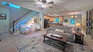 A spacious living room with a staircase, a kitchen, and a dining area. - Colston Creek- Nestled in the Trees with a beautiful creekside space (Bryson City)