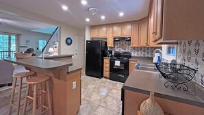 A modern kitchen with wooden cabinets, a black refrigerator, and a stainless steel sink. - Colston Creek- Nestled in the Trees with a beautiful creekside space (Bryson City)